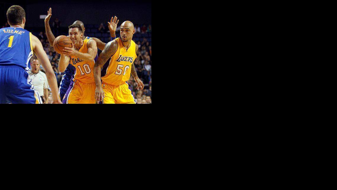 Los Angeles Lakers guard Steve Nash (10) takes a shot with center Robert Sacre (50) looking on against Golden State Warriors center Ognjen Kuzmic (1), of Bosnia, and guard Leandro Barbosa, of Brazil, from behind during the first half of a preseason NBA basketball game, Sunday, Oct. 12, 2014, in Ontario, Calif.