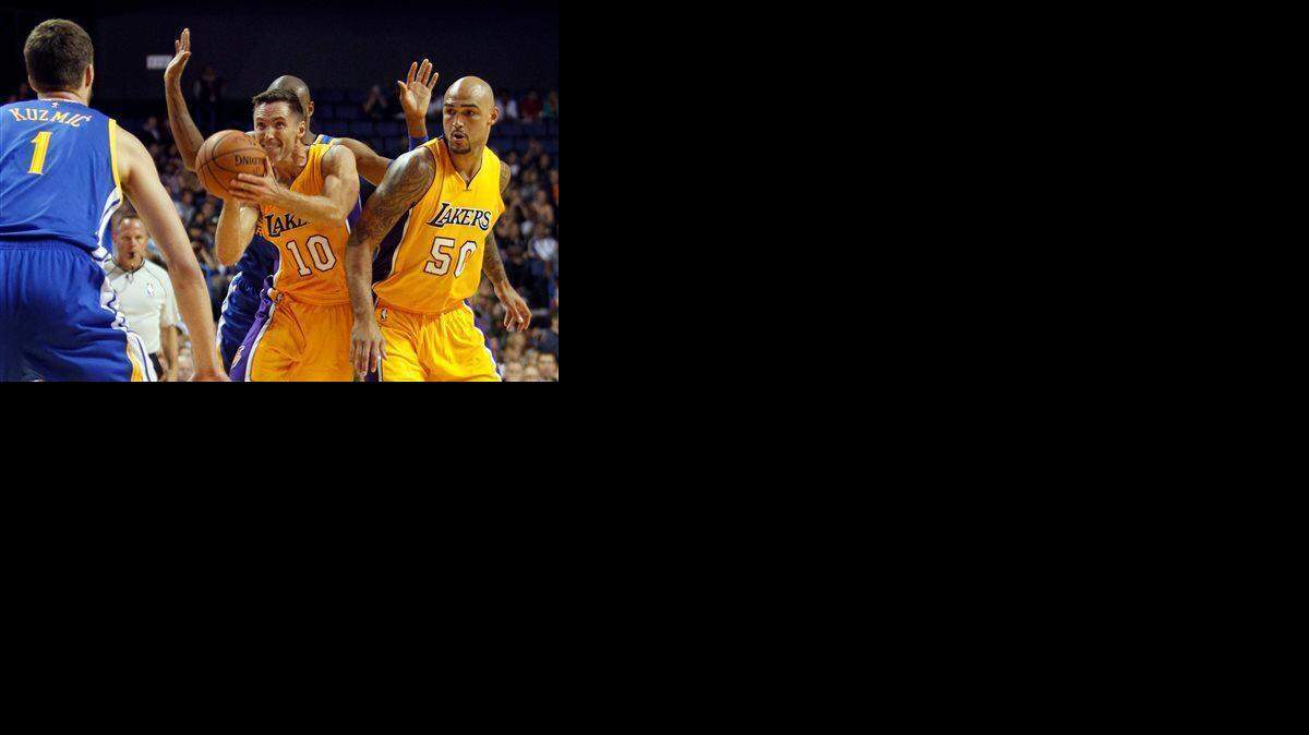 Los Angeles Lakers guard Steve Nash (10) takes a shot with center Robert Sacre (50) looking on against Golden State Warriors center Ognjen Kuzmic (1), of Bosnia, and guard Leandro Barbosa, of Brazil, from behind during the first half of a preseason NBA basketball game, Sunday, Oct. 12, 2014, in Ontario, Calif.