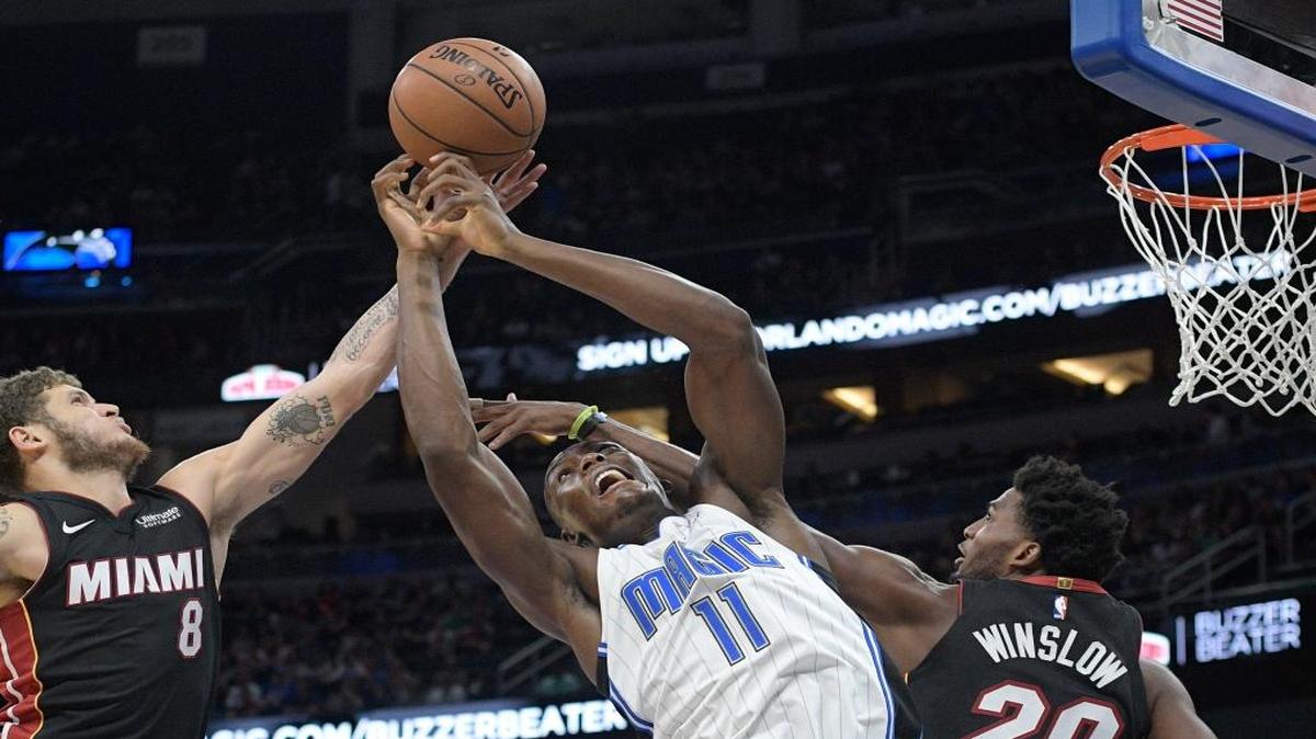 Orlando Magic center Bismack Biyombo (11) fights for a rebound between Miami Heat guard Tyler Johnson (8) and forward Justice Winslow (20) during the first half of an NBA basketball game Saturday, Oct. 7, 2017, in Orlando, Fla.