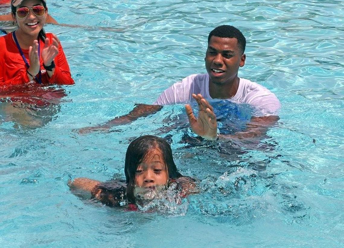 Miami Heat center Hassan Whiteside helps Laura Cartayn, 6, swim at North Pointe YMCA Family Center pool at its 2015 camp.