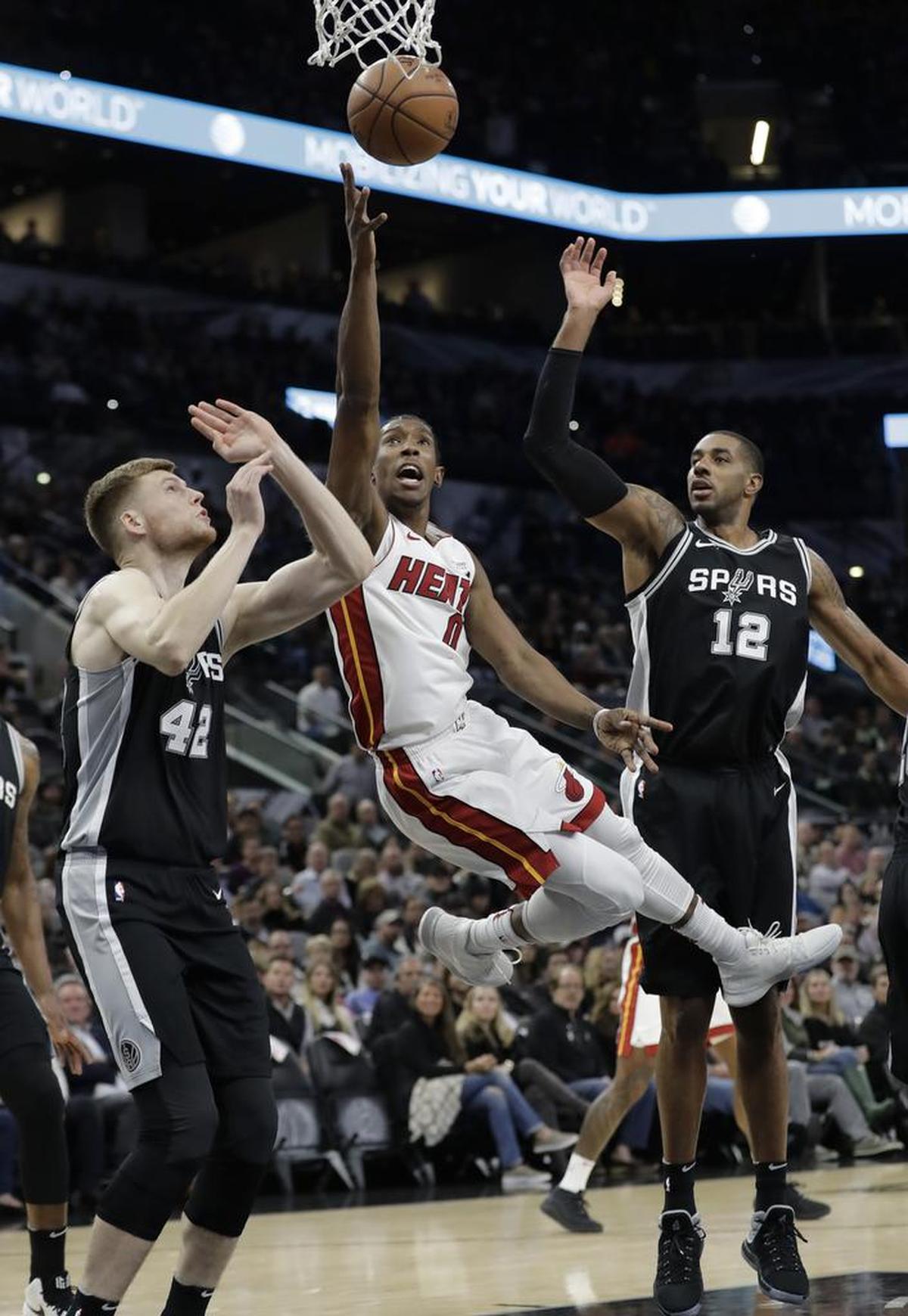Miami Heat forward Josh Richardson (0) shoots between San Antonio Spurs defenders Davis Bertans (42) and LaMarcus Aldridge (12) during the first half of an NBA basketball game Wednesday, Dec. 6, 2017, in San Antonio.