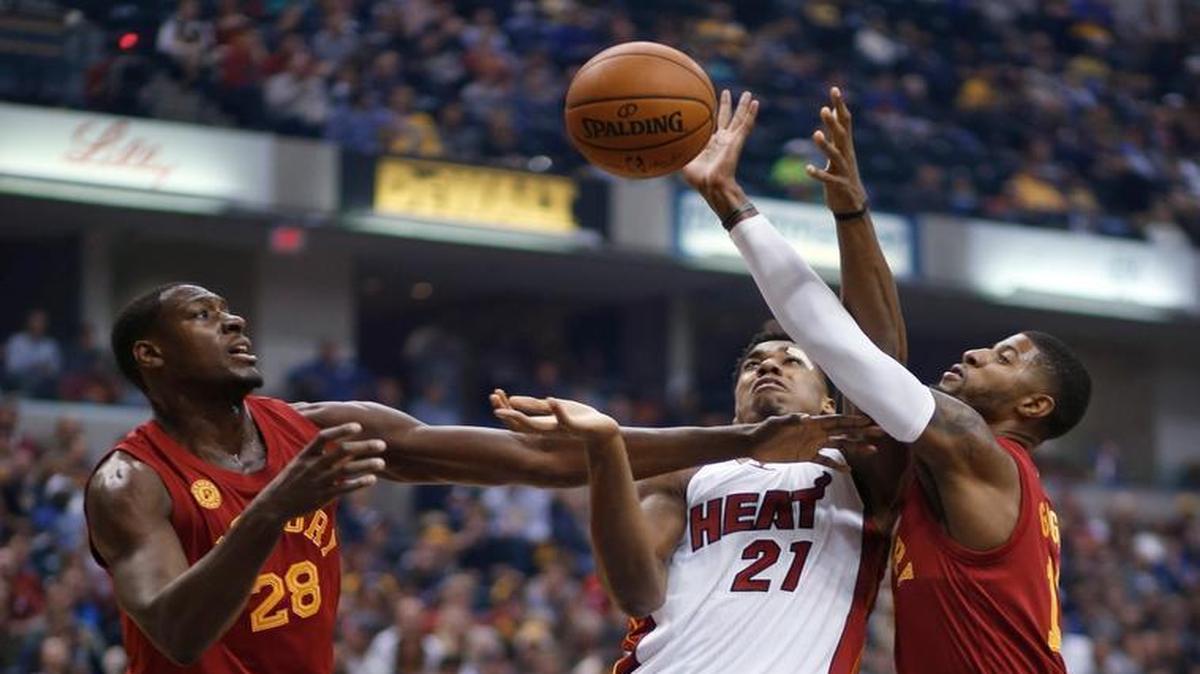 Miami Heat center Hassan Whiteside, center, goes for a rebound between Pacers defenders Ian Mahinmi, left, and Paul George during the first half of an NBA basketball game in Indianapolis, Friday, Nov. 6, 2015.