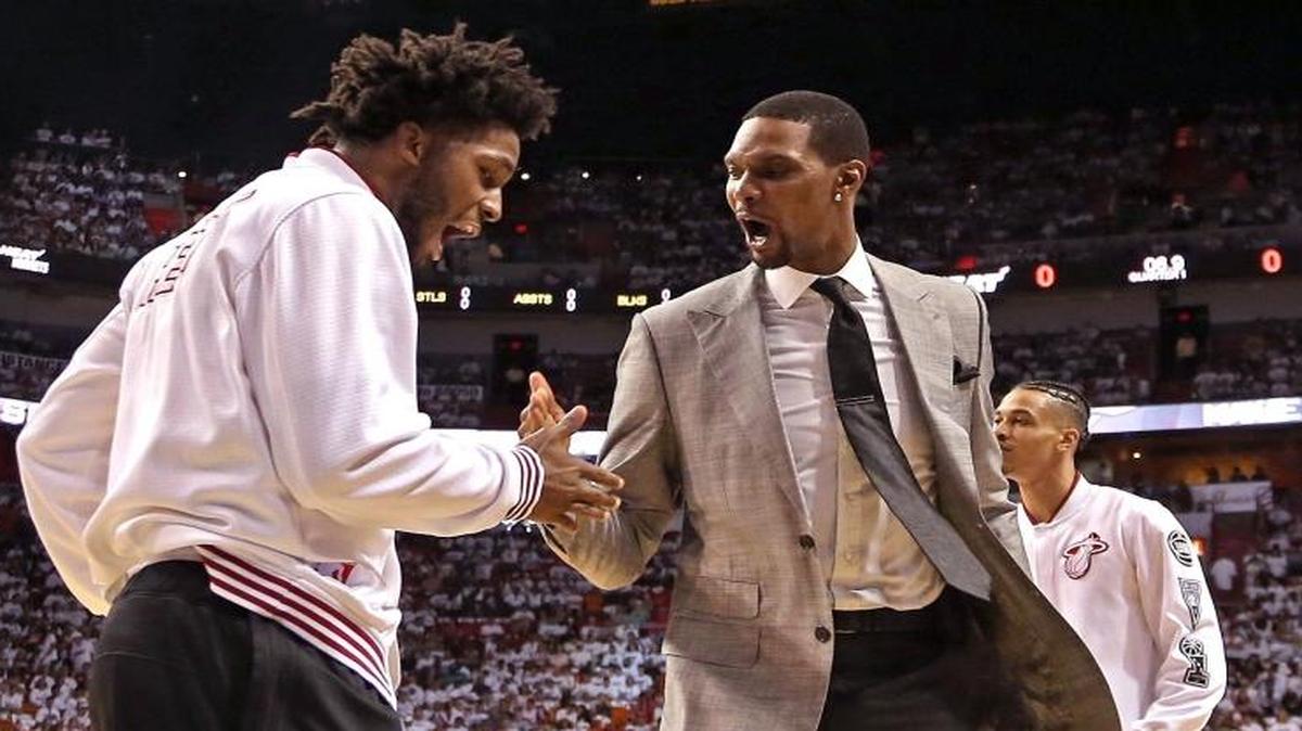 Chris Bosh, right, gives his support from the bench with Justise Winslow before Game 1 of the Heat-Hornets series.