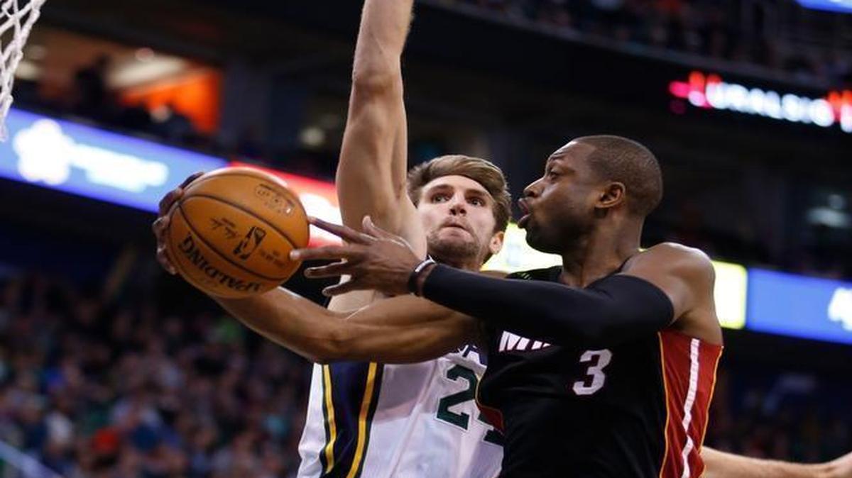 Miami Heat guard Dwyane Wade, right, lays a shot in past Utah Jazz center Jeff Withey, left, during an NBA basketball game Saturday, Jan. 9, 2016, in Salt Lake City.
