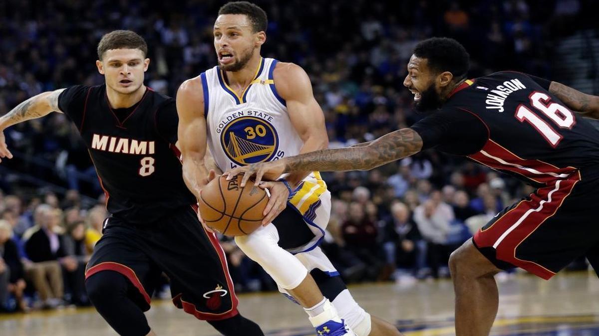 Golden State Warriors' Stephen Curry (30) drives between Miami Heat's Tyler Johnson (8) and James Johnson (16) during the second half of an NBA basketball game Tues., Jan. 10, 2017, in Oakland, Calif. Golden State won 107-95.