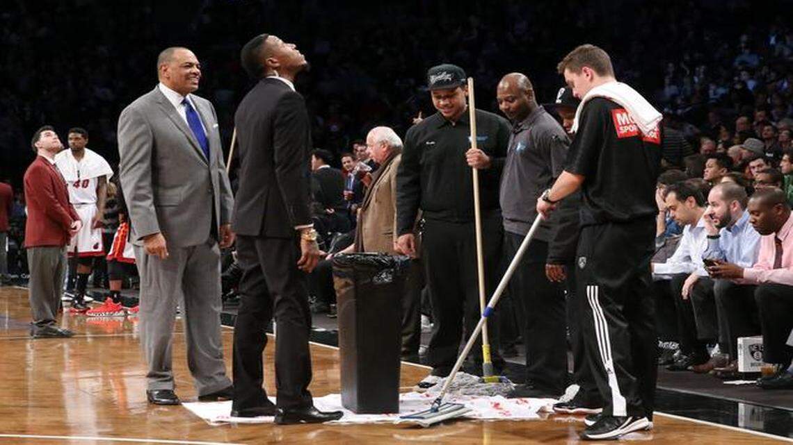 
Interruption: Nets coach Lionel Hollins, left, stands beside floor attendants as a roof leak causes a delay in the first half Brooklyn’s game against the Heat.
