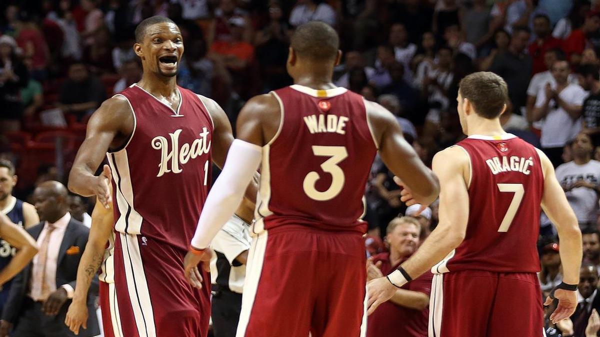 Dwyane Wade and Goran Dragic greet Chris Bosh of the Miami Heat after a Bosh basket to break a tie against the New Orleans Pelicans in the fourth quarter of a game at AmericanAirlines Arena in Miami on Thursday, December 25, 2015.