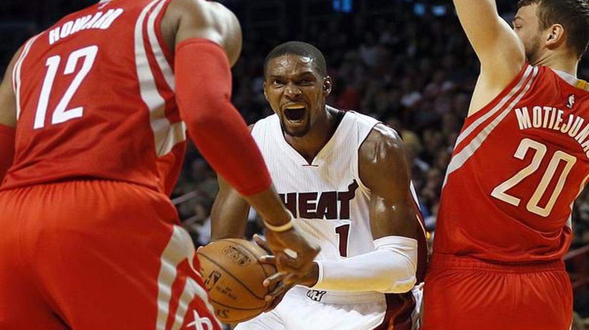 Miami Heat's Chris Bosh drives to the basket against Rockets' Dwight Howard and Donatas Motiejunas in the second quarter of the Miami Heat's game against the Houston Rockets at AmericanAirlines Arena in Miami on Tuesday, Nov. 4, 2014.