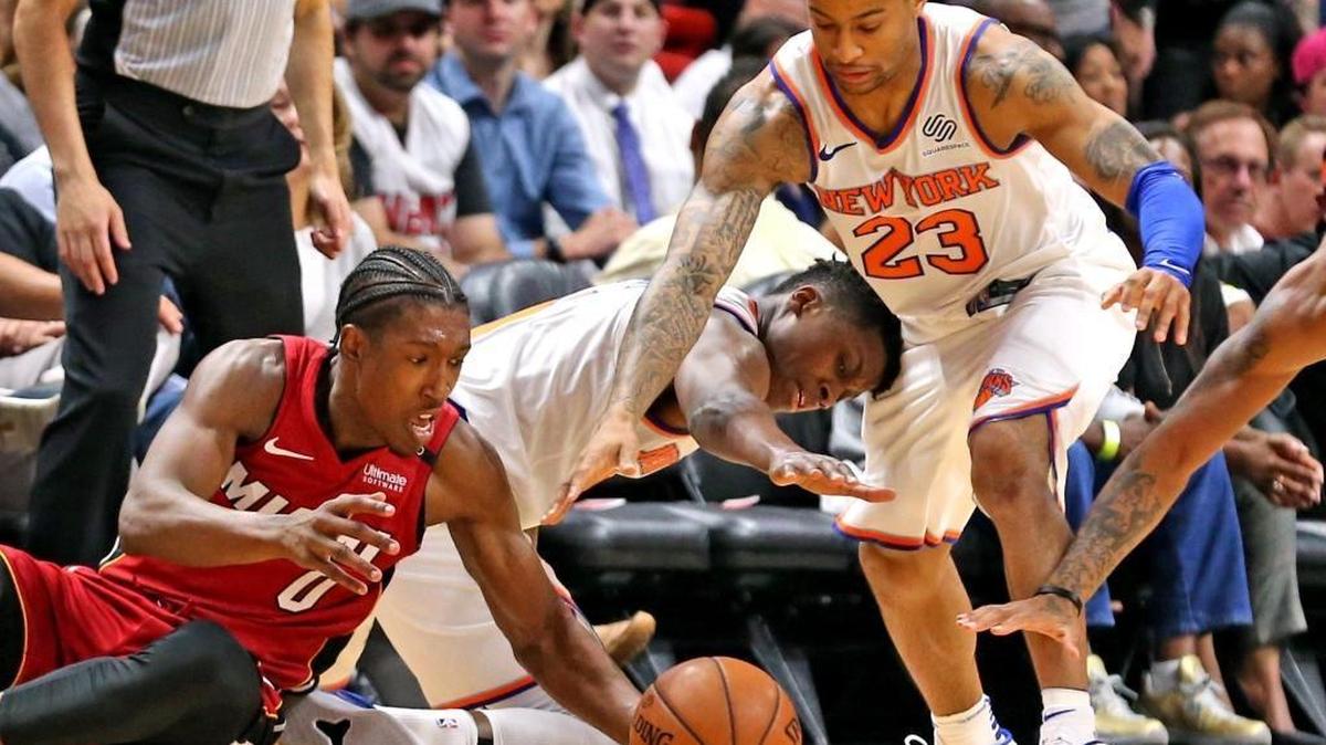 Miami Heat forward Josh Richardson and New York Knicks guard Trey Burke try to get a ball on the court in the second quarter at the AmericanAirlines Arena in Miami, Florida, March 21, 2018.