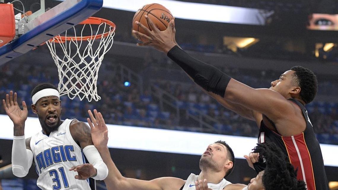 Miami Heat center Hassan Whiteside, right, puts up a shot over Orlando Magic guard Terrence Ross (31), center Nikola Vucevic, second from left, and guard Elfrid Payton during the first half of an NBA basketball game Wednesday, Oct. 18, 2017, in Orlando, Fla.