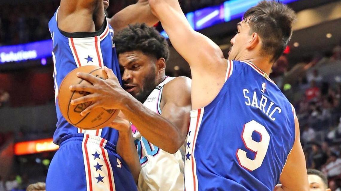 Miami Heat’s Justise Winslow squeezes between Philadelphia 76ers’ Joel Embiid (21) and Dario Saric (9) in the first quarter Tuesday, Feb. 27, 2018, at the AmericanAirlines Arena in Miami. Embiid has been sidelined with an injury near his left eye.