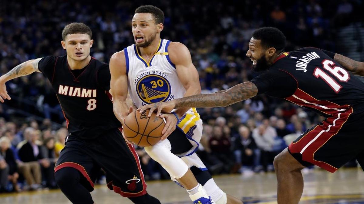 Golden State Warriors' Stephen Curry (30) drives between Miami Heat's Tyler Johnson (8) and James Johnson (16) during the second half of an NBA basketball game Tuesday, Jan. 10, 2017, in Oakland, Calif. Golden State won 107-95.