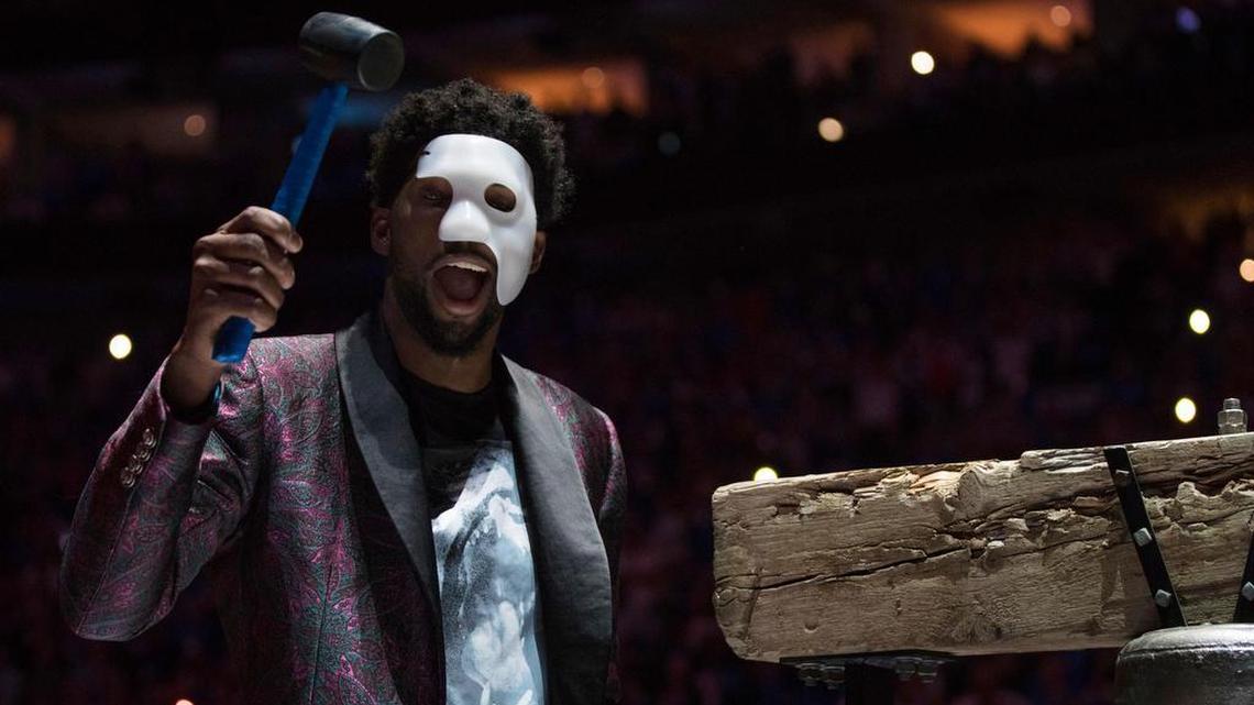Philadelphia 76ers' Joel Embiid, in the wake of a fractured orbital bone near his left eye, comes out in a "Phantom of the Opera" mask as he rings a Liberty Bell replica before Game 1 of the team's first-round NBA basketball playoff series against the Miami Heat, Saturday, April 14, 2018, in Philadelphia. The 76ers say Embiid is probable for Thursday's Game 3.