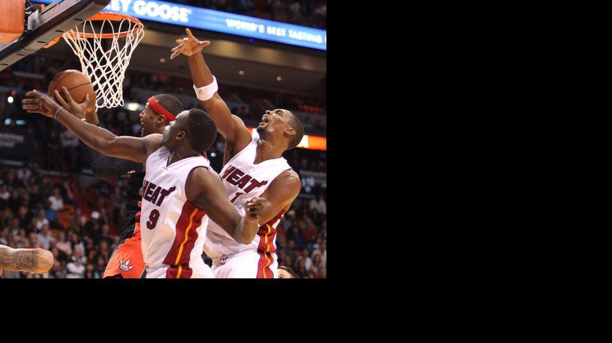 
Miami Heat’s Loul Deng (9) and Chris Bosh (1) trying to block the shot of Toronto Raptors’ James Johnson in the second quarter at the AmericanAirlines Arena on Sunday, Nov. 2, 2014.
