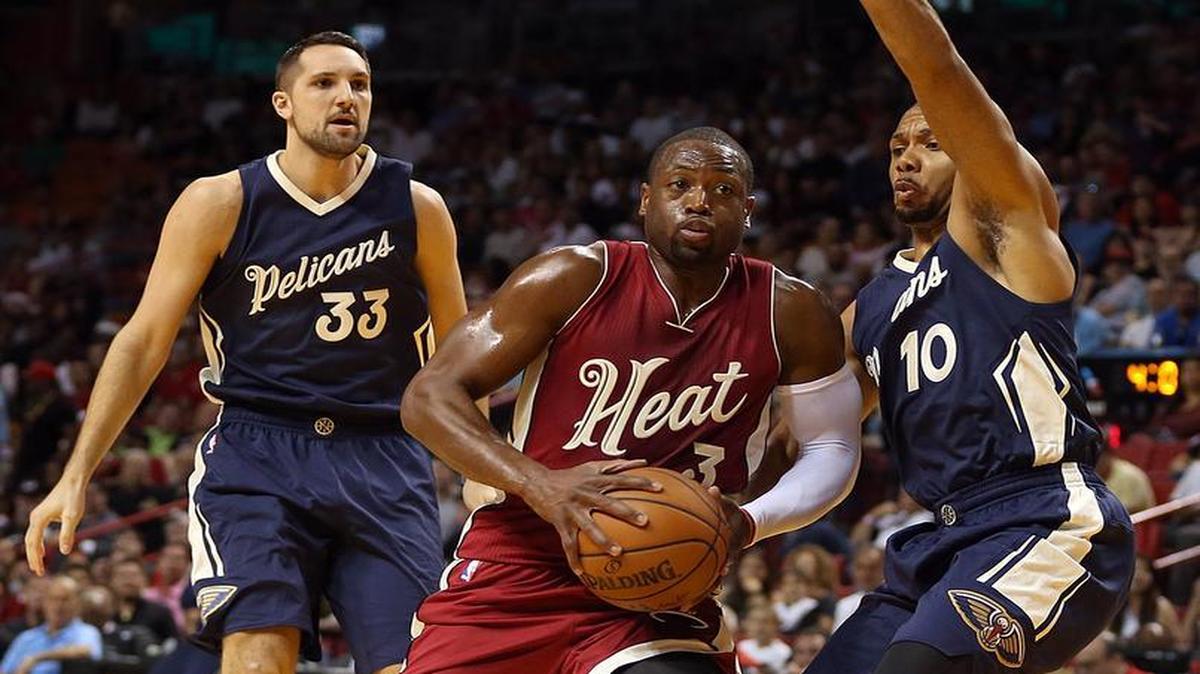 Dwyane Wade of the Miami Heat drives against Ryan Anderson #33 and Eric Gordon #10 of the New Orleans Pelicans in the first quarter of a game at AmericanAirlines Arena in Miami on Thursday, December 25, 2015.