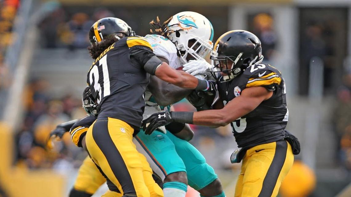 Miami Dolphins Jay Ajayi is tackled by Pittsburgh Steelers Ross Cockrell 31, and Mike Mitchell 23, in the second quarter in the NFL Wild-Card Playoffs at Heinz Stadium, Pittsburgh, PA, January 8, 2017.