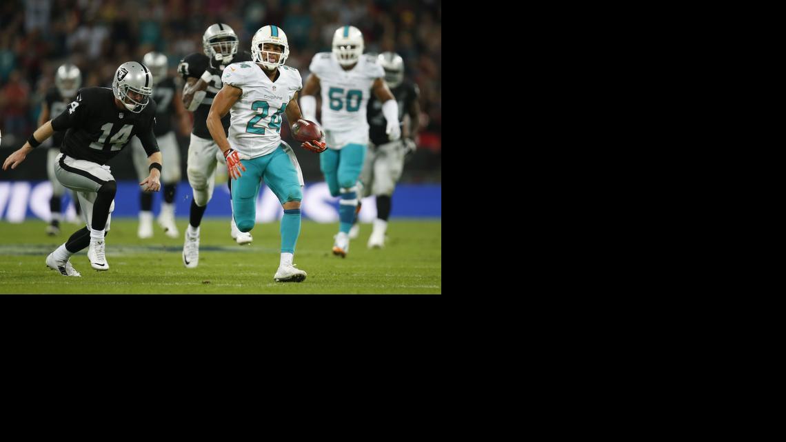 
Miami Dolphins' Cortland Finnegan, right, returns a fumbled snap for a touchdown past Oakland Raiders' Matt McGloin during the second half of an NFL football game against the Oakland Raiders, Sunday, Sept. 28, 2014, at Wembley Stadium in London. 
