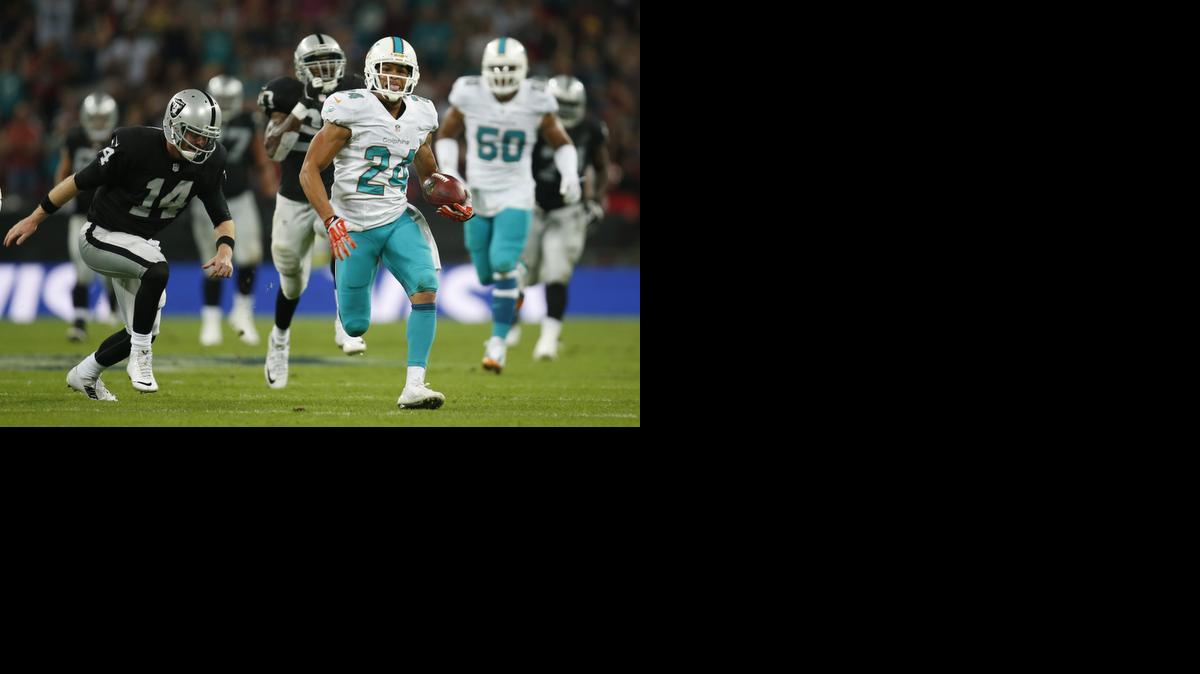 
Miami Dolphins' Cortland Finnegan, right, returns a fumbled snap for a touchdown past Oakland Raiders' Matt McGloin during the second half of an NFL football game against the Oakland Raiders, Sunday, Sept. 28, 2014, at Wembley Stadium in London. 

