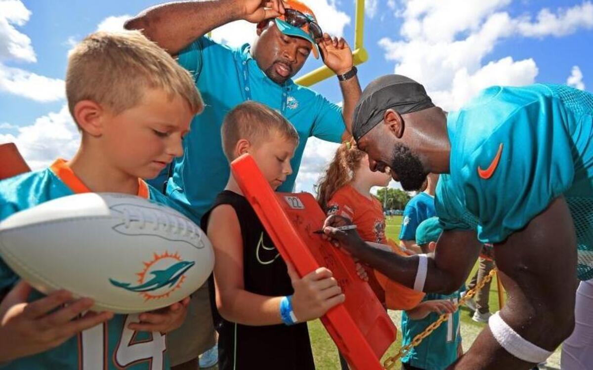 Michael Thomas signs a fans chair back from a stadium after Miami Dolphins football practice in July.