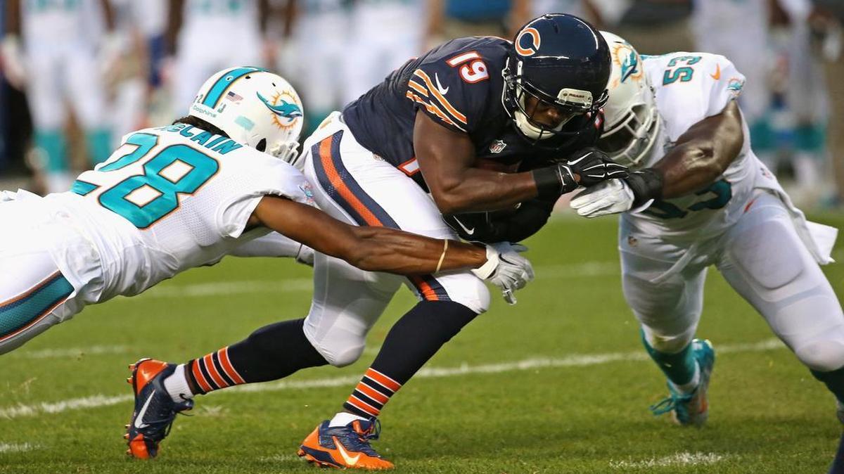 
Eddie Royal #19 of the Chicago Bears is hit after a catch by Jamar Taylor #22 and Jelani Jenkins #53 of the Miami Dolphins during a preseason game at Soldier Field on August 13, 2015 in Chicago, Illinois. 
