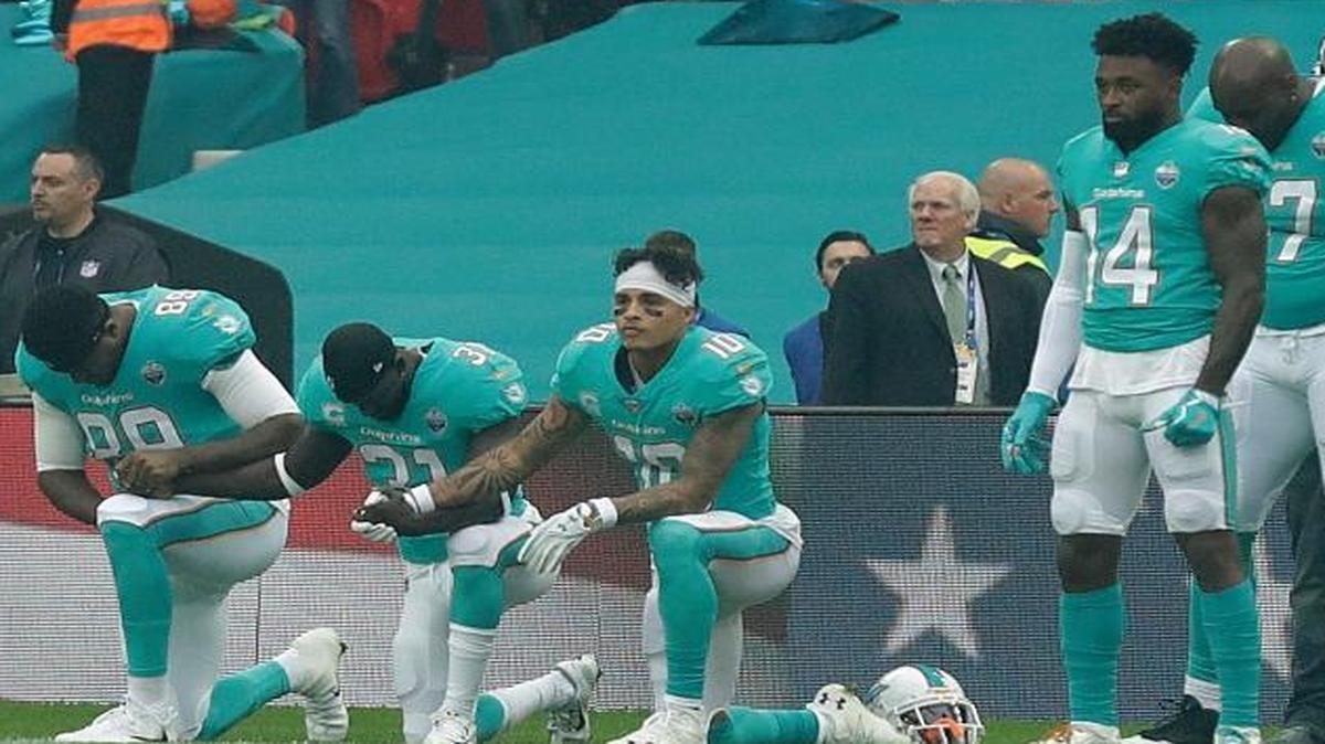 Miami Dolphins' Julius Thomas (89), Michael Thomas (31) and Kenny Stills take a knee as the U.S. national anthem is played before an NFL football game against the New Orleans Saints at Wembley Stadium in London, Sunday Oct. 1, 2017.