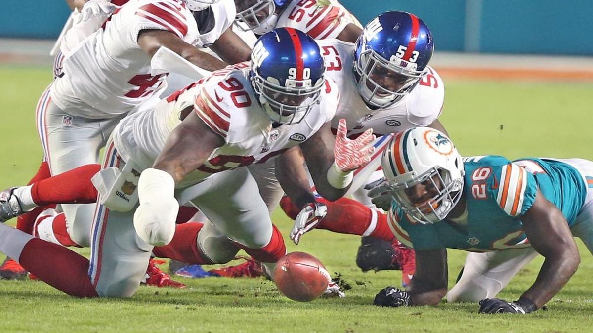 Lamar Miller watches as Jason Pierre-Paul recovers a fumble in the first quarter of the Miami Dolphins’ game against the New York Giants at Sun Life Stadium in Miami Gardens on December 14, 2015.