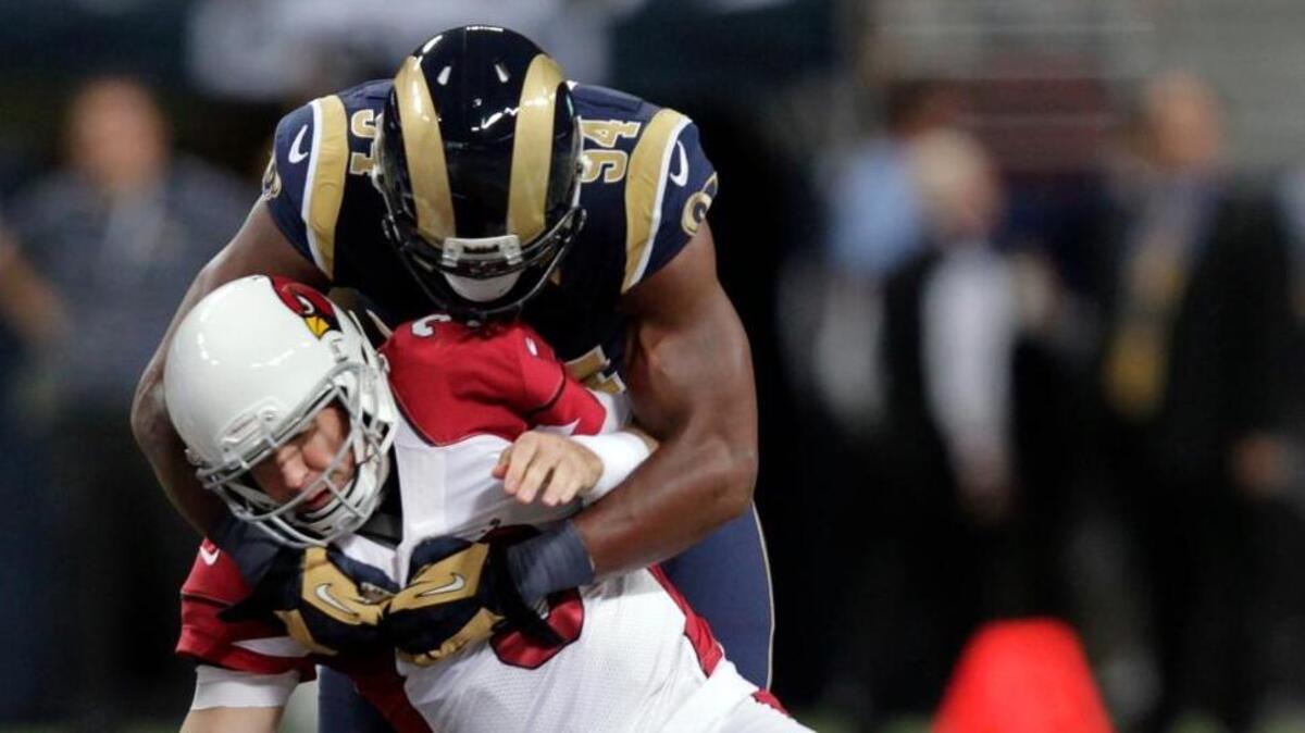 Arizona Cardinals quarterback Carson Palmer, bottom, fumbles the ball as he is sacked for a 7-yard loss by St. Louis Rams defensive end Robert Quinn during the first quarter of an NFL football game on Sunday, Sept. 8, 2013, in St. Louis. The Cardinals recovered the fumble.