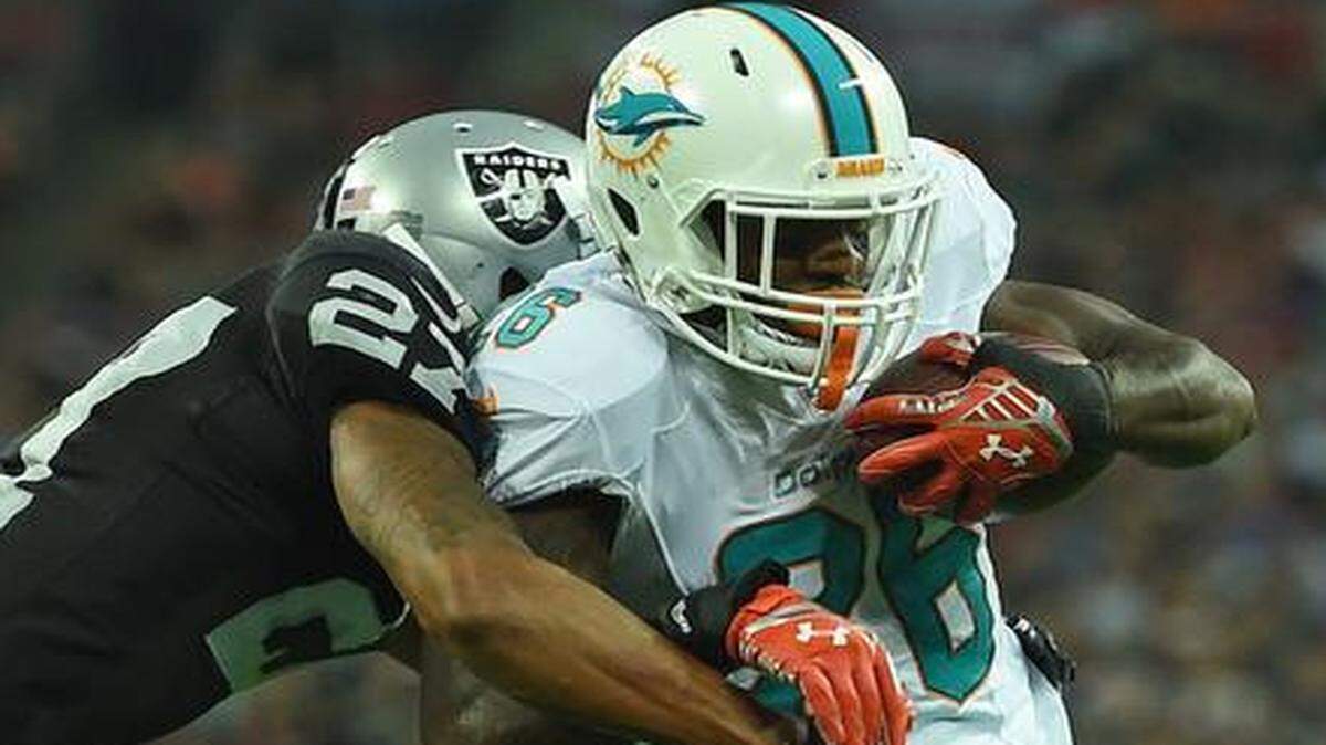 
Miami Dolphins' Lamar Miller, right, breaks a tackle on his way to scoring a touchdown during the NFL football game against Oakland Raiders at Wembley Stadium in London, Sunday, Sept. 28, 2014.

