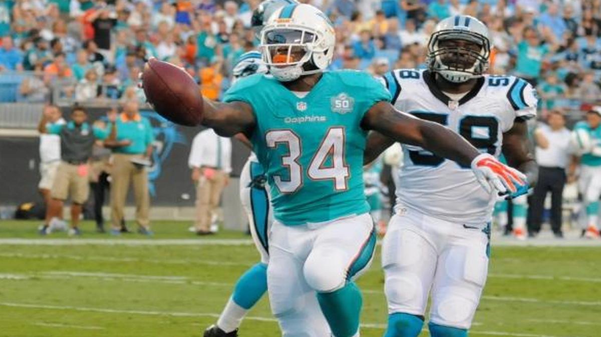 
Miami Dolphins’ Damien Williams (34) runs past Carolina Panthers' Thomas Davis (58) for a touchdown during a preseason game in Charlotte, N.C., Saturday, Aug. 22, 2015. 
