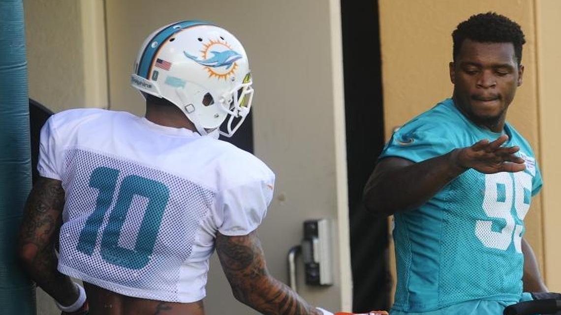 Rehabbing Miami Dolphins defensive end Dion Jordan gives receiver Kenny Stills a high-five during training camp.