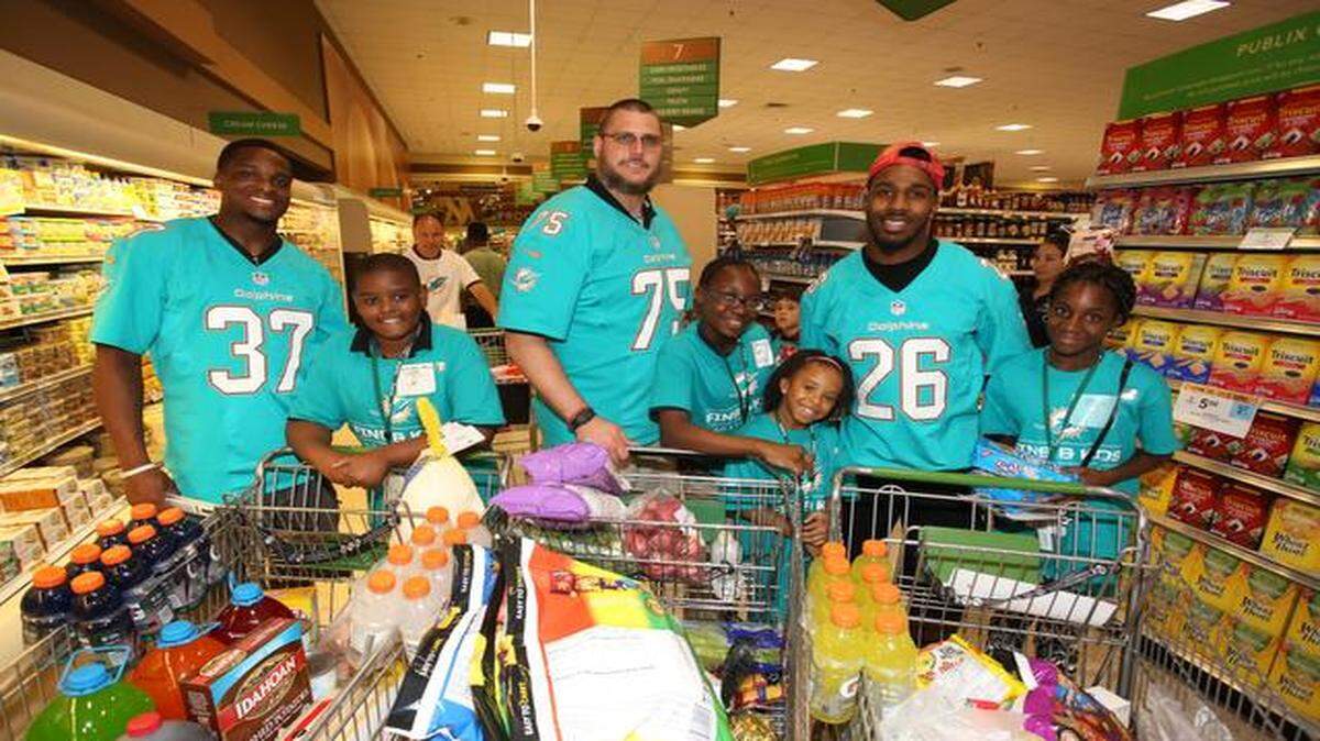 
Miami Dolphins players Lamar Miller, Nate Garner and Sammy Seamster shop with students at the Kids and Fins event with Publix 
