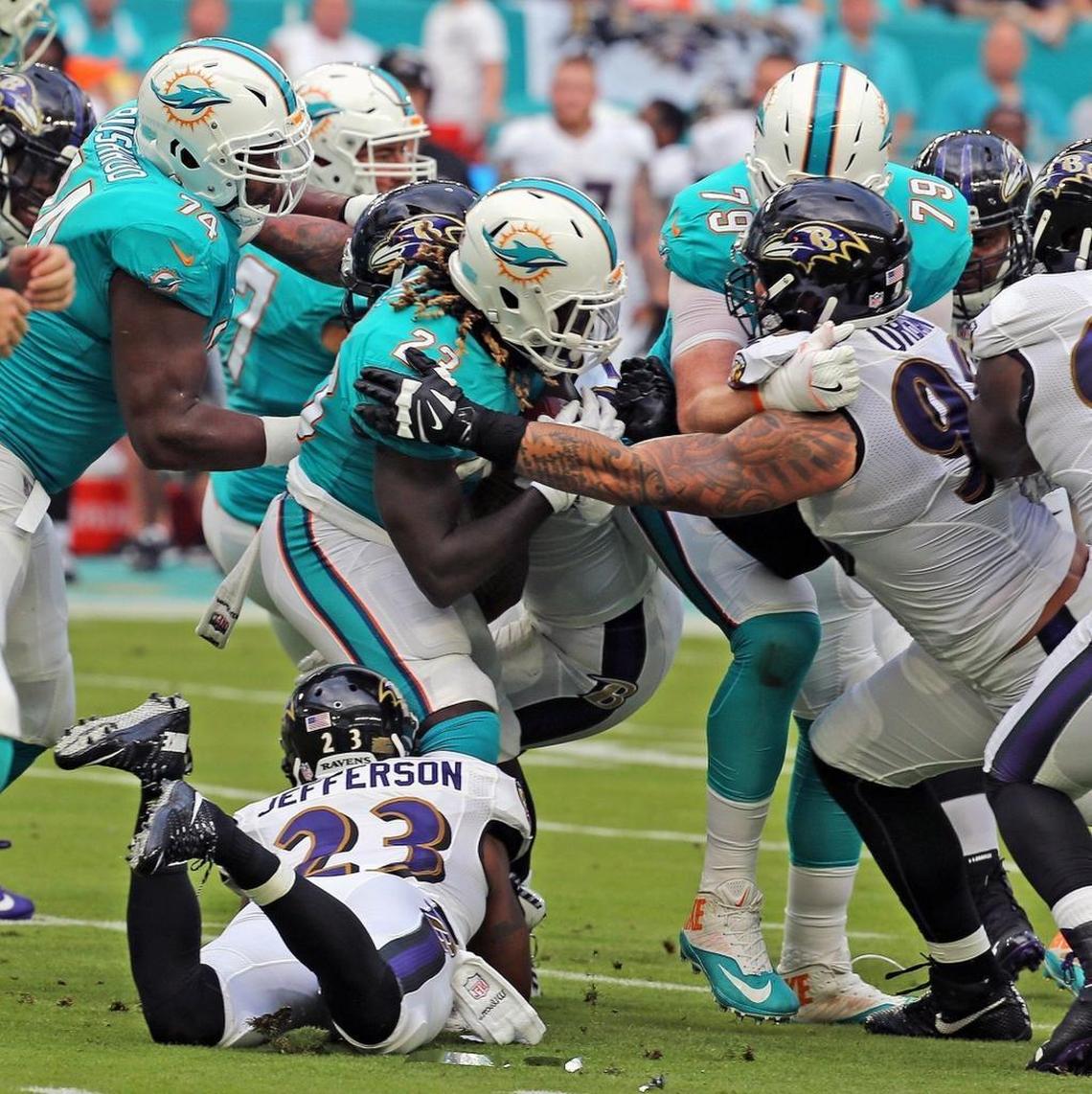 Dolphins Jay Ajayi (23) is tackled by Ravens Brent Urban (96) and Tony Jefferson (23) in the first quarter as the Miami Dolphins play the Baltimore Ravens in their second preseason game at Hard Rock Stadium in Miami Gardens, FL, Aug. 17, 2017.