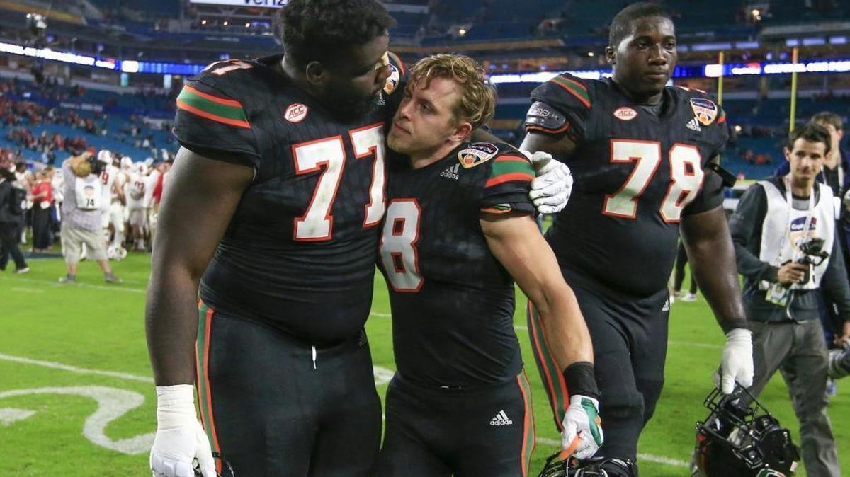 Miami Hurricanes offensive lineman Jahair Jones (77) and Miami Hurricanes wide receiver Braxton Berrios (8) embrace after UM’s Orange Bowl loss to Wisconsin.