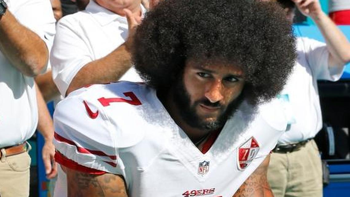 San Francisco 49ers quarterback Colin Kaepernick, right, and outside linebacker Eli Harold take a knee during the national anthem as the Miami Dolphins host the 49ers at Hard Rock Stadium in Miami Gardens on Sunday, Nov. 27, 2016