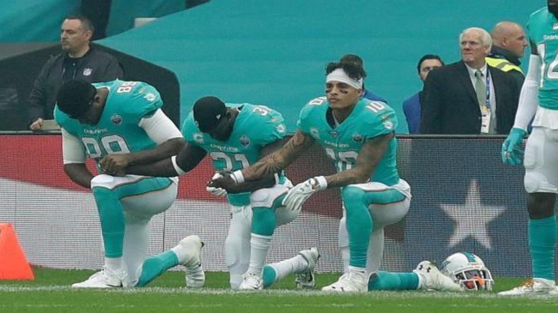 Miami Dolphins' Julius Thomas (89), Michael Thomas (31) and Kenny Stills take a knee as the U.S. national anthem is played before an NFL football game against the New Orleans Saints at Wembley Stadium in London, Sunday Oct. 1, 2017.