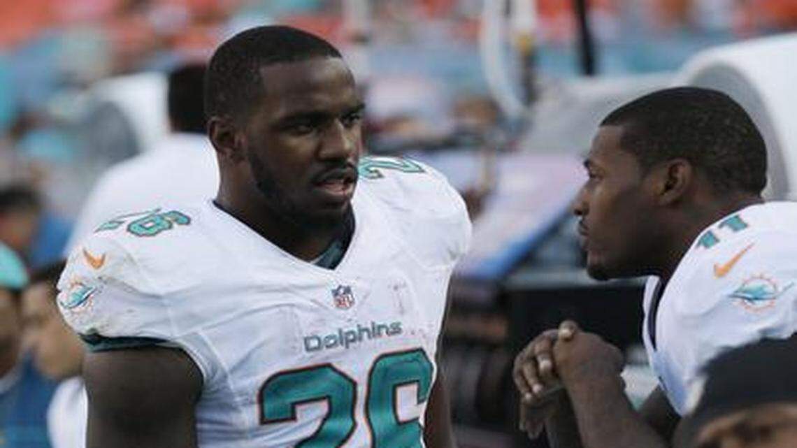 
Just a spectator: Mike Wallace, right, who didn’t play in the second half against the Jets on Sunday at Sun Life Stadium, talks with running back Lamar Miller.
