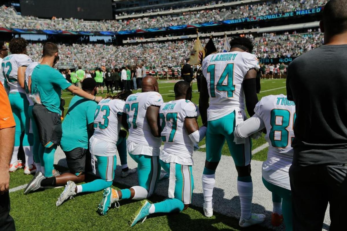 Miami Dolphins offensive tackle Laremy Tunsil (67), Maurice Smith (27), and Jarvis Landry (14) lock hands with teammates during the playing of the national anthem before a game against the New York Jets Sunday, Sept. 24, 2017, in East Rutherford, N.J.