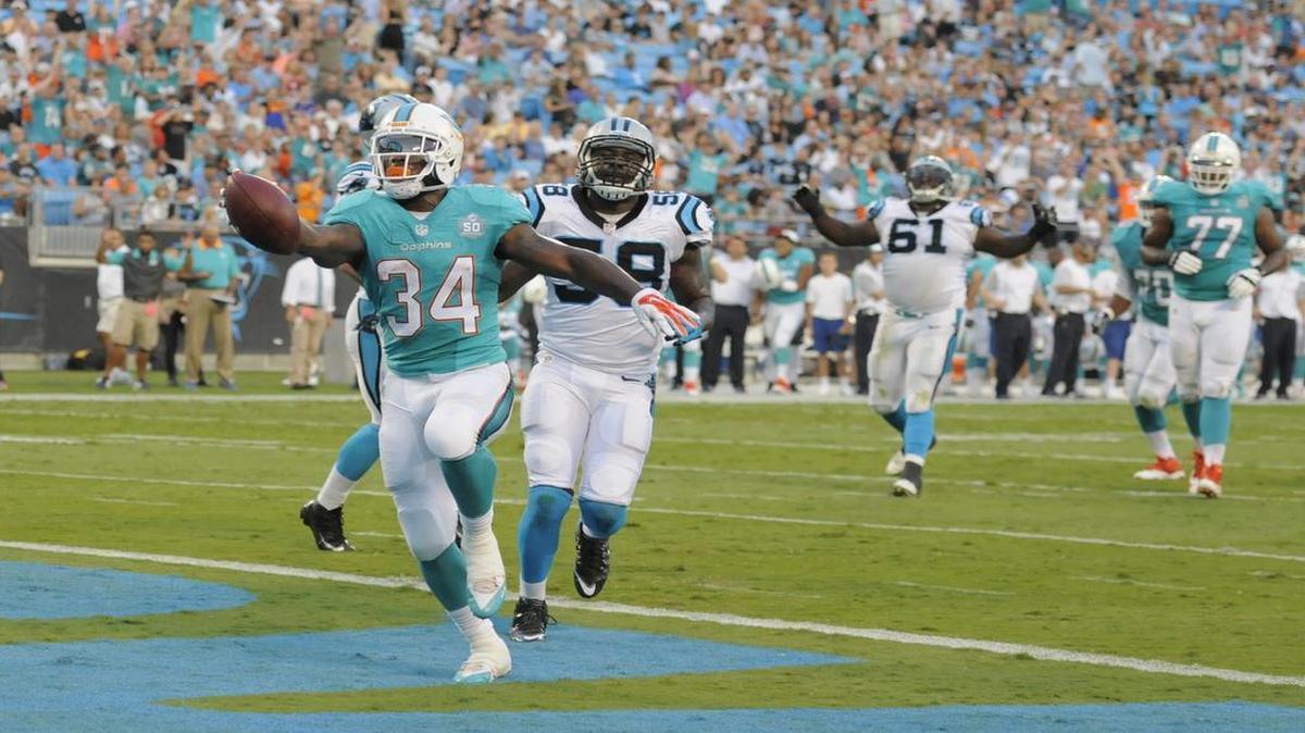 
Miami Dolphins' Damien Williams (34) runs past Carolina Panthers' Thomas Davis (58) for a touchdown during the first half of an NFL preseason football game in Charlotte, N.C., Saturday, Aug. 22, 2015. 
