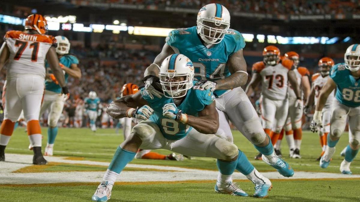 Defensive tackle Randy Starks piles on Cameron Wake after he sacks Andy Dalton for a safety in overtime of the game with the Miami Dolphins and the Cincinnati Bengals at Sun Life Stadium in Miami Gardens on Oct., 31, 2013.
