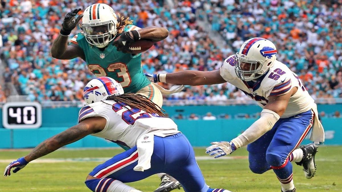 Miami Dolphins Jay Ajayi runs the ball in the third quarter to help set up a touchdown as Buffalo Bills Ronald Darby 28, and Preston Brown 52, defend at Hard Rock Stadium in Miami Gardens, Florida on Sun., Oct. 23, 2016.