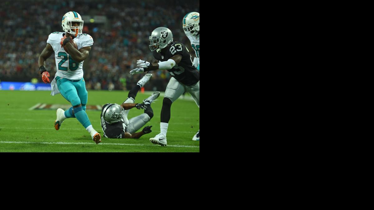 
Miami Dolphins' Lamar Miller races into the end zone to score a touchdown during the NFL football game against Oakland Raiders at Wembley Stadium in London, Sunday, Sept. 28, 2014. 
