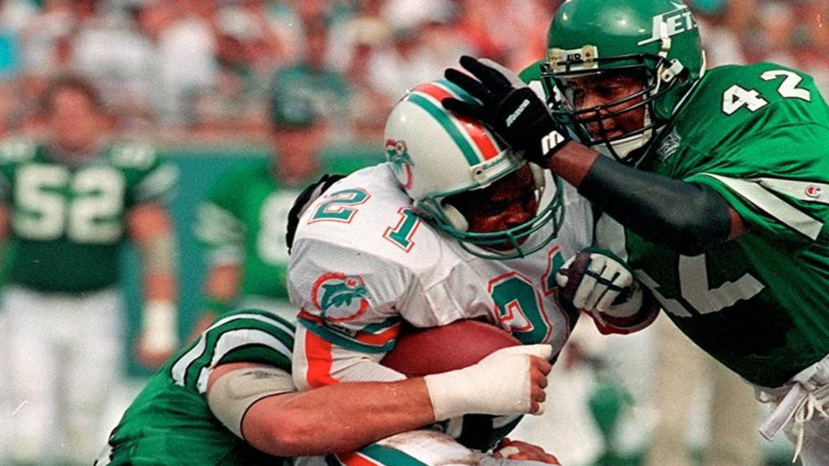Mark Higgs is tackled by Jeff Lageman, left, and Ronnie Lott, right, during the Miami Dolphins’ game against the New York Jets on Sept. 13, 1993.