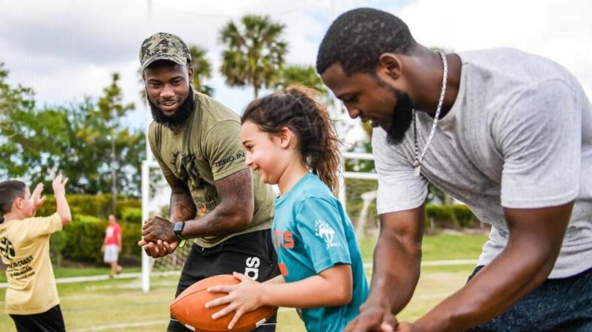 Miami Dolphins receivers Malcolm Lewis (left) and Rashawn Scott (right) help lead drills during a free football clinic in Parkland.