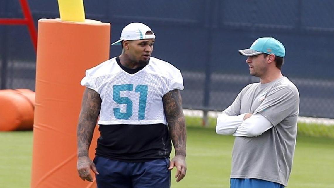 Injured center Mike Pouncey talks with coach Adam Gase during practice at the Miami Dolphins.