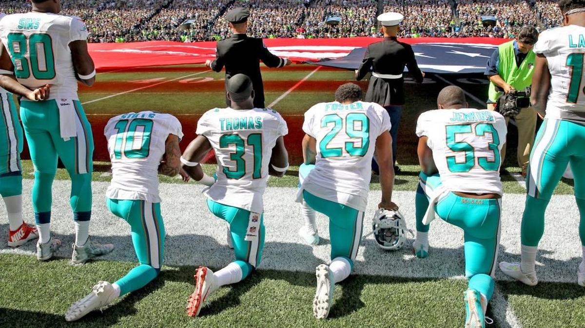 Miami Dolphins Jelani Jenkins, Arian Foster, Michael Thomas and Kenny Stills kneel in protest during the national anthem prior to their game against the host Seattle Seahawks on Sunday afternoon.