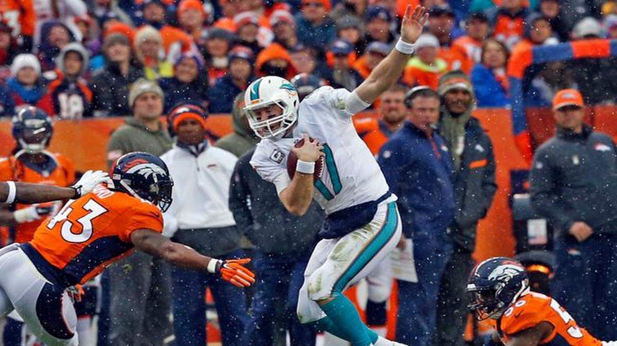 
Miami Dolphins quarterback Ryan Tannehill tries to dodge Denver Broncos defender T.J. Ward in the second quarter as a light snow falls at Sports Authority Field at Mile High in Denver, Colorado, Nov. 23, 2014.
