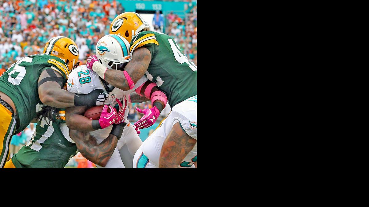 
Miami Dolphins Knowshon Moreno is stopped by Green Bay Packers defensive lineman Mike Daniels (76) and Morgan Burnett (42) as Moreno attempts to score on fourth down after the Dolphins blocked a punt deep in Packers territtory in the first quarter at Sun Life Stadium in Miami Gardens on Oct. 12, 2014.
