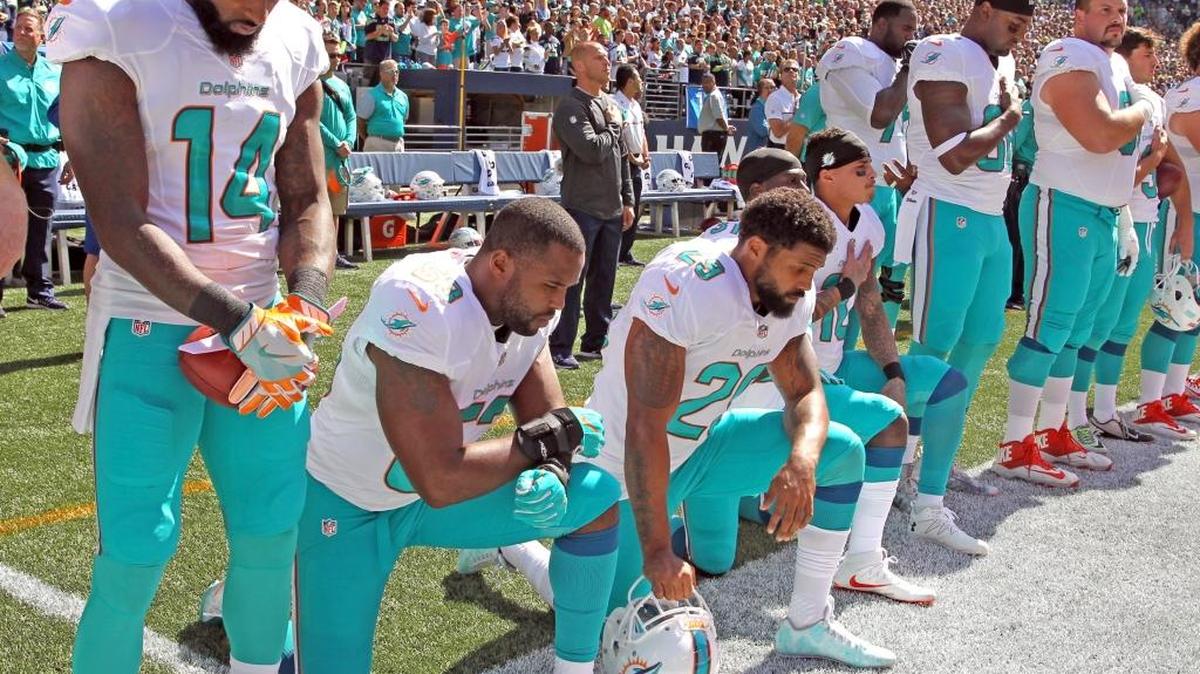 Miami Dolphins players Jelani Jenkins, Arian Foster, Michael Thomas and Kenny Stills kneel in protest during the national anthem as the Fins prepare to play the Seattle Seahawks at CenturyLink Field in Seattle on Sunday, Sept. 11, 2016.