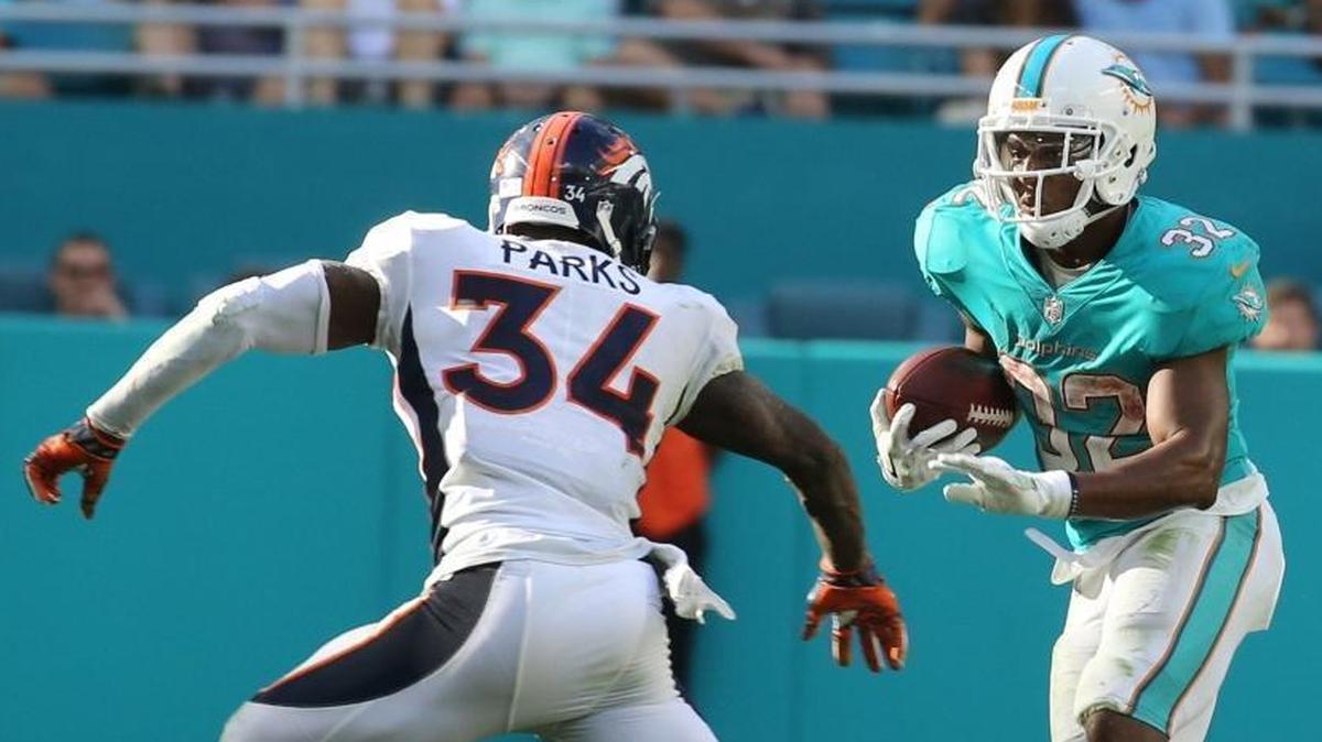 Miami Dolphins running back Kenyan Drake (32) looks to dodge Denver’s Will Parks (34) in the third quarter of the game at Hard Rock Stadium on Dec. 3, 2017.