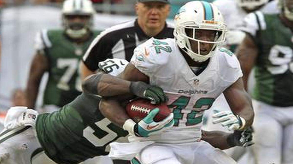 
Dolphins tight end Charles Clay is tackled by the Jets’ Demario Davis at Sun Life Stadium in Miami Gardens, Florida, Dec. 29, 2013.
